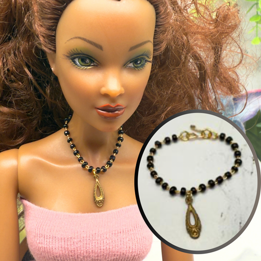 Black Glass Beaded Gold Teardrop Pendant Doll Necklace. Necklace measures 3.25 inches long. Necklace shown on 16” Spellbound Valentina doll