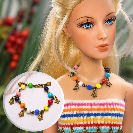 Add a pop of color to your doll's outfit with this multi-color bead dangle flower charm necklace. This necklace measures 3 3/4 inches in length. Necklace shown on 16-inch Madame Alexander - Alex doll