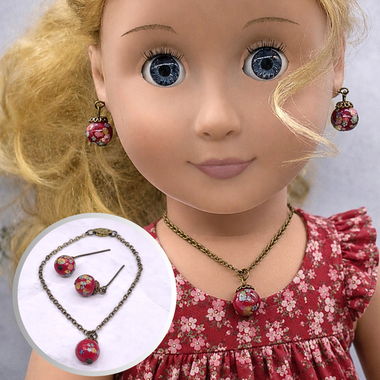 Add a pop of color to your doll's outfit with this Red glass Drop Pendant Doll Necklace Earrings Set. The set includes a red pendant necklace and matching earrings with floral design. The necklace measures 6.5 in length. Necklace and earrings shown on 18" Our Generation doll